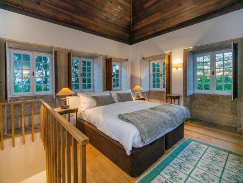 a bedroom with a large bed and windows at Casas de Massinos in Barroselas
