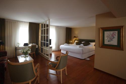 a hotel room with a bed and a table and chairs at Suites del Bosque Hotel in Lima