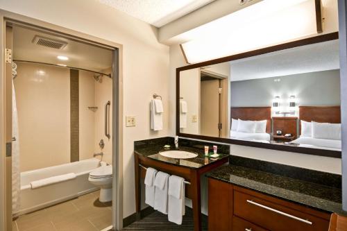 a bathroom with a sink and a toilet and a mirror at Hyatt Place Dallas North in Addison