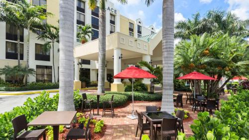 a patio with tables and umbrellas in front of a hotel at Hyatt Place Fort Lauderdale Cruise Port & Convention Center in Fort Lauderdale