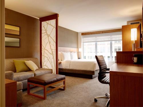 a hotel room with a bed and a couch and a chair at Hyatt Place Arlington Courthouse in Arlington