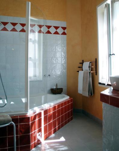 La salle de bains est pourvue d'une baignoire et d'une douche avec du carrelage rouge. dans l'établissement Domaine de Provensol, à Venterol