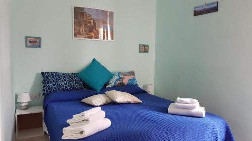 una camera da letto con un letto blu e asciugamani di A Casa di Arturo a Napoli