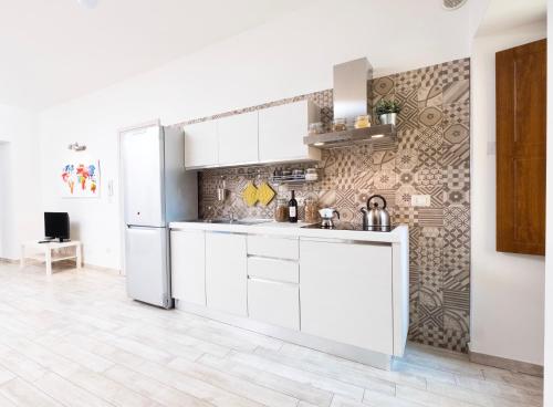 a kitchen with white cabinets and a refrigerator at Apollo Home in Catania