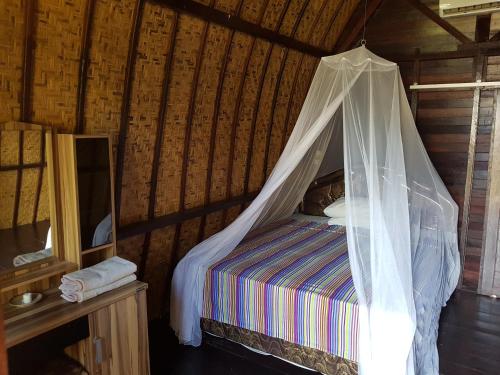 a bedroom with a bed with a mosquito net at Sasak Island Bungalows in Gili Meno