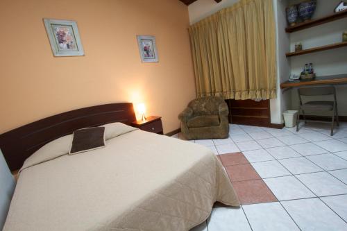 a bedroom with a bed and a chair and a desk at Comfort Hostel in Guatemala