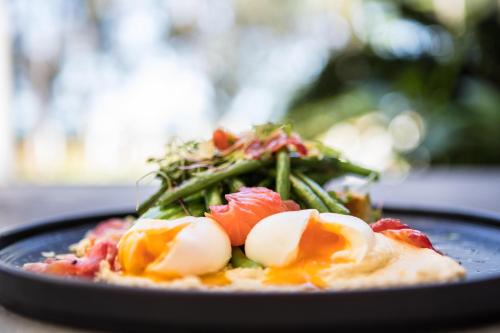 Un plato de comida con huevos y espárragos. en Port Douglas Peninsula Boutique Hotel - Adults Only Haven, en Port Douglas