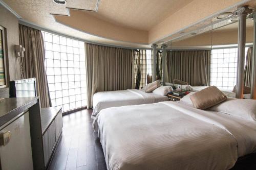 two beds in a hotel room with windows at Katherine Plaza Hotel in Kaohsiung