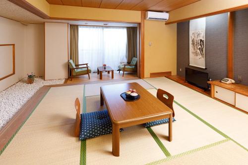 - un salon avec une table, des chaises et une télévision dans l'établissement 雅竹Miyabitake, à Yugawara