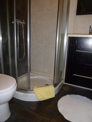 a bathroom with a shower with a yellow towel on the floor at Porto's City Park & Surf Beach Rooms in Matosinhos