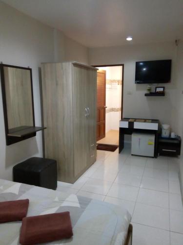 a living room with a wooden cabinet and a television at Living Room Guesthouse & Cafe Bar in Karon Beach