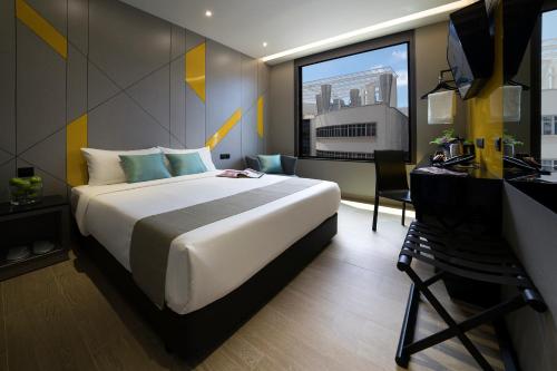 a hotel room with a bed and a desk and a window at Hotel Mi in Singapore