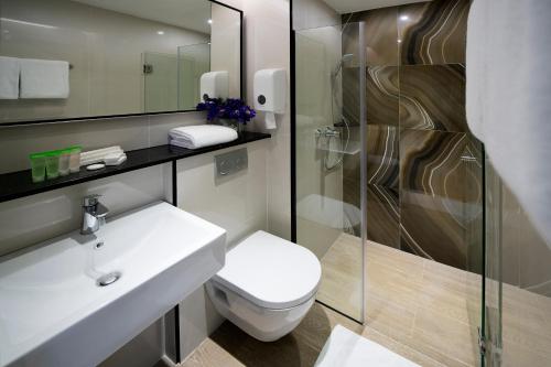 a bathroom with a toilet and a sink and a shower at Hotel Mi Bencoolen in Singapore