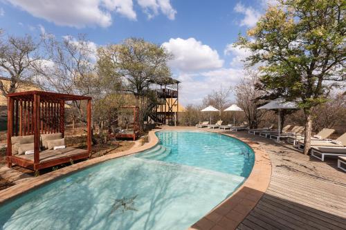a large swimming pool with a wooden deck next to at Unembeza Boutique Lodge & Spa in Hoedspruit