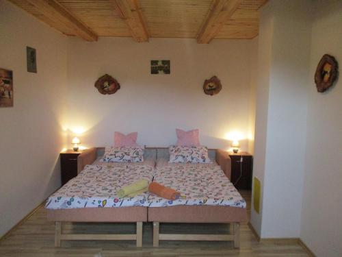 ein Schlafzimmer mit einem Bett mit zwei Lampen an der Wand in der Unterkunft Pagony Pihenő Farm in Orfalu