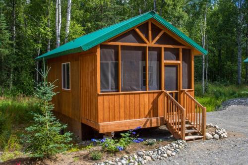 a cabin in the woods with a green roof at Talkeetna Wilderness Lodge & Cabin Rentals in Sunshine