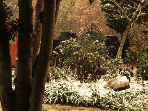 a snow covered garden with a bridge in the background at Villa La Clef Des Champs in Chailly-en-Bière