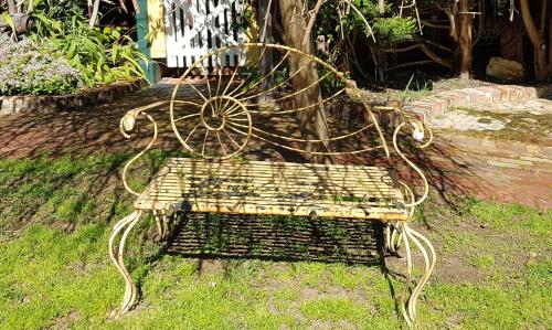 an old metal bench sitting in the grass at Bridgefield Guest House in Margaret River Town