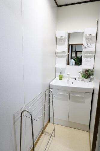a white bathroom with a sink and a mirror at GUEST HOUSE E-NINE in Kyoto
