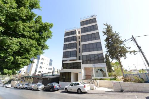 Un edificio alto con coches aparcados delante. en Grand Park Hotel Jerusalem, en Jerusalén