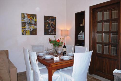 a dining room with a table and white chairs at Lemon Tree and Olive Garden House in Chorto