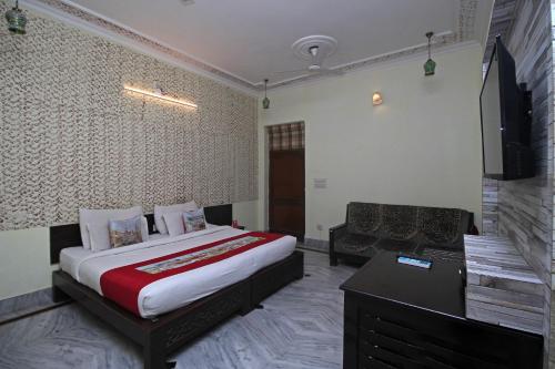 a bedroom with a bed and a desk and a television at Elysium Ecotel in Jaipur