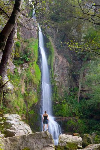 a man standing on a rock in front of a waterfall at Hotel Arenas de Cabrales- apartamentos in Arenas de Cabrales