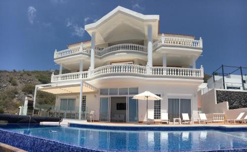 a large white house with a swimming pool in front of it at Villa Sunset View Tenerife, Simply Amazing in Adeje