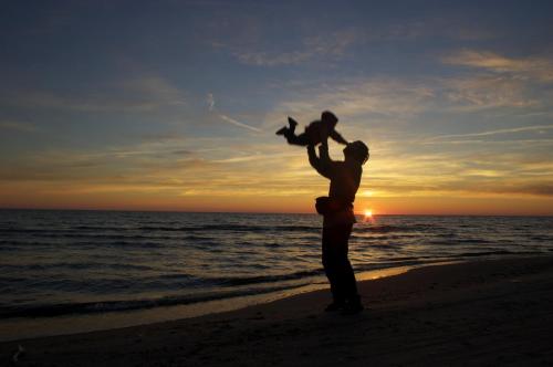 a man standing on the beach with a child on his shoulders at Vērbeļnieki in Pērkone