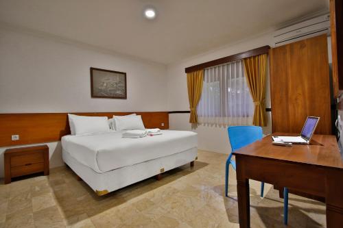 a bedroom with a bed and a desk and a laptop at The Jayakarta Anyer in Anyer