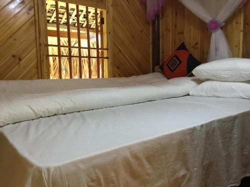 two white beds in a room with a window at Chô Family in Bắc Hà