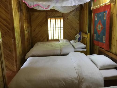a room with three beds in a wooden cabin at Chô Family in Bắc Hà