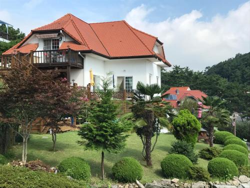 a white house with an orange roof at Namhae Frankfurt Pension in Namhae