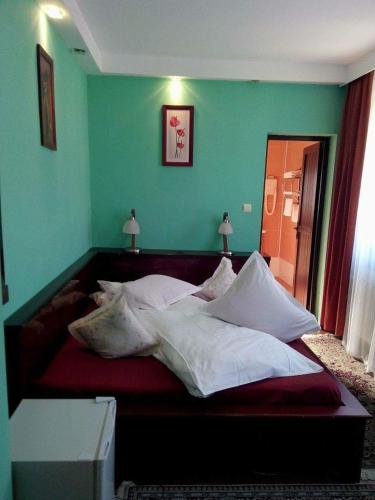 a large bed in a green room with two lamps at Vila Bratocea in Cheia