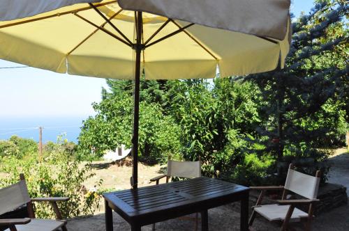 a black table with a yellow umbrella and chairs at Red Villa's Guesthouse in Tsagarada