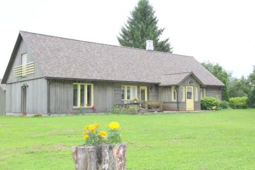 a small house with yellow flowers in a yard at Karu Holiday Home in Laiusevälja