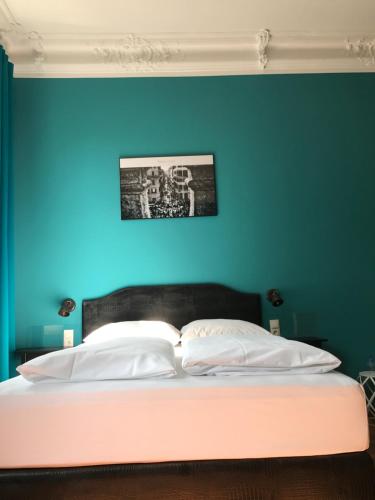 a bedroom with a blue wall and a bed with white pillows at SmartHotel Mystique Self check-in in Bad Homburg vor der Höhe