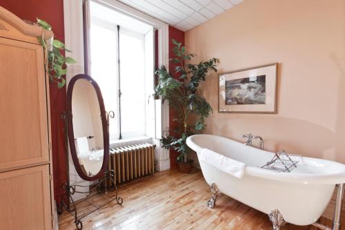 a bathroom with a large white tub and a window at Manoir Sur le Cap in Quebec City