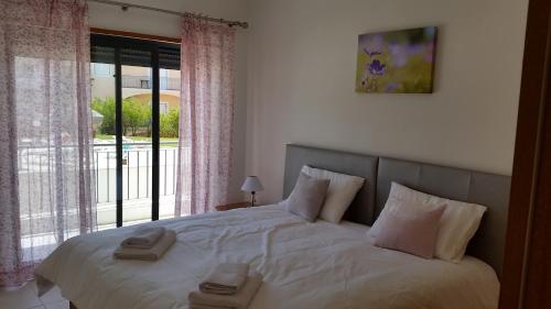 a bedroom with a large bed with two towels on it at Vista das Ondas Olhos de Agua in Albufeira
