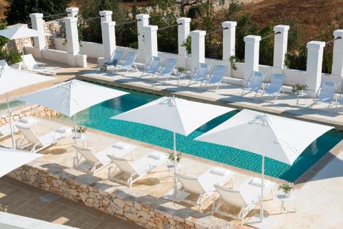 a group of chairs and umbrellas next to a swimming pool at Masseria Le Torri in Polignano a Mare