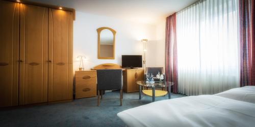 a bedroom with a bed and a desk and a table at Hotel Pfälzer Hof in Braunschweig