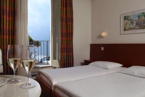 a hotel room with a bed and two wine glasses at Piazza Ascona Hotel & Restaurants in Ascona