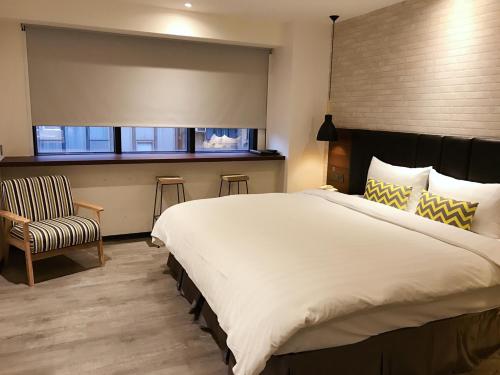 a bedroom with a large bed and a chair at Goldinn Hotel in Taipei