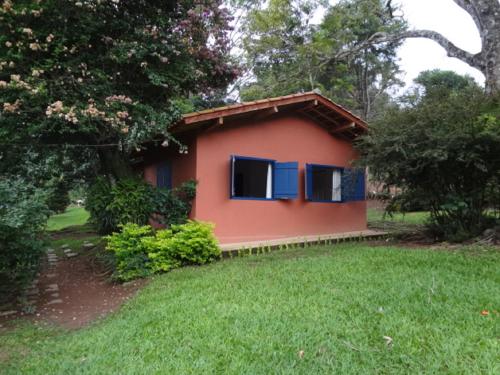 ein kleines Haus mit blauen Fenstern im Hof in der Unterkunft Chalés Del'Minas in Passa Quatro