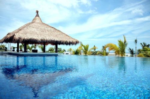 a resort swimming pool with a thatch hut and palm trees at The Cliff Residence in Mui Ne