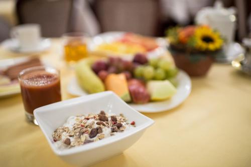 a table with a bowl of cereal and a plate of fruit at Hotel Austria - Wien in Vienna