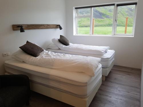 two beds in a room with a window at Bólstaðarhlíð Guesthouse in Bólstaðarhlíð