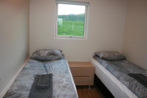 two beds in a room with a window at Eyvindartunga farm cottage in Laugarvatn