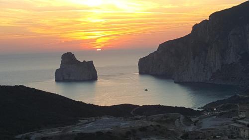 una puesta de sol sobre el océano con rocas en el agua en Tanca Piras - Emozioni a strapiombo sul Mare!!!, en Nebida