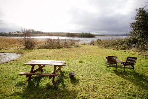 a picnic table and a bench next to a lake at Erinona Chalet in Kesh